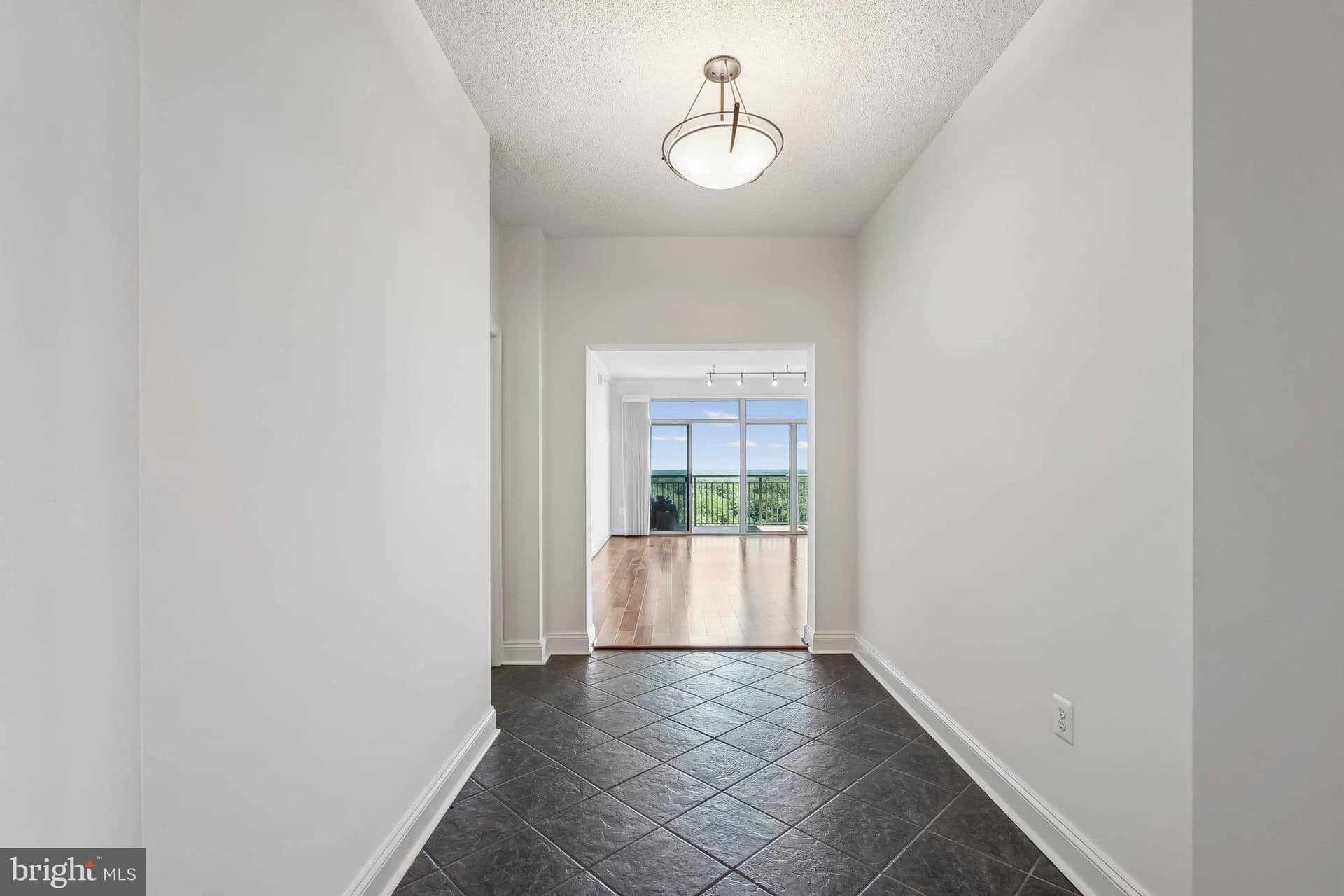 Unit 1103 entry hall with dark tile flooring opening toward the sunlit wood-floored living areas