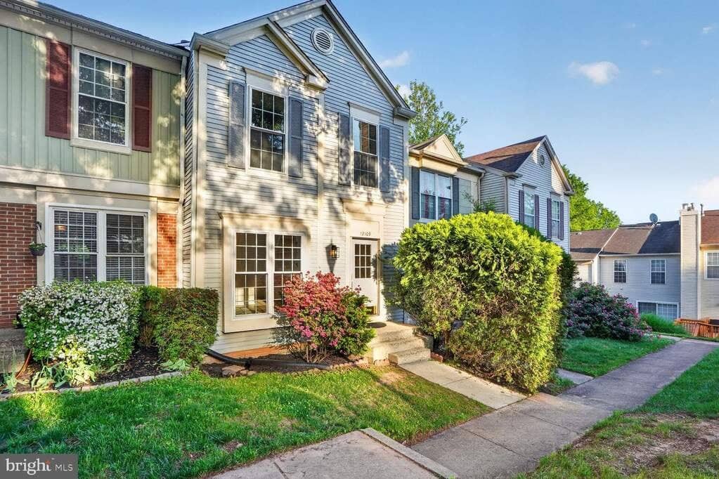 Angled front exterior of 12109 Wedgeway Place showing the end-unit setting and mature landscaping