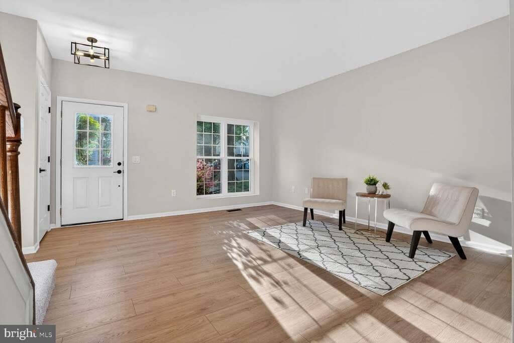 Renovated main-level living room with luxury vinyl plank flooring, paired windows, and the front entry
