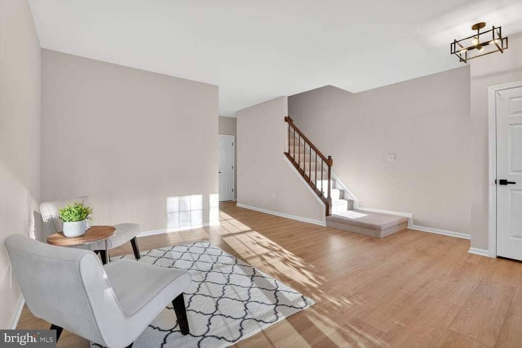 Open living room viewed toward the staircase and dining area with continuous luxury vinyl plank flooring