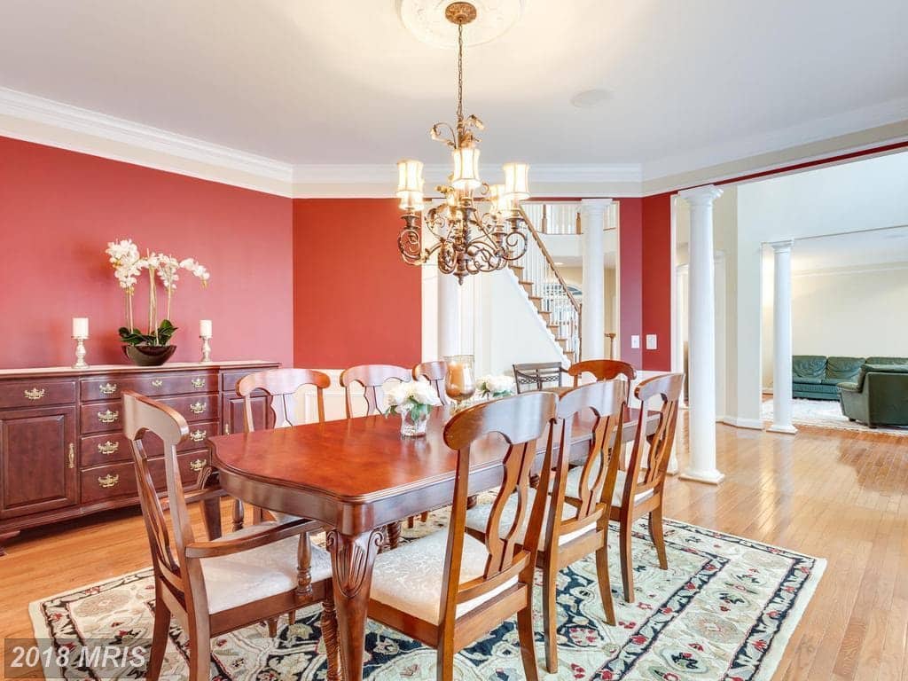 Formal dining room at 12803 Holly Grove Court with hardwood floors, a chandelier, and a columned opening