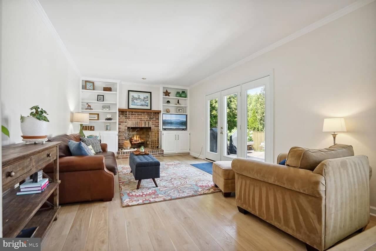 Family room with brick wood-burning fireplace, built-in shelving, and French doors to the deck