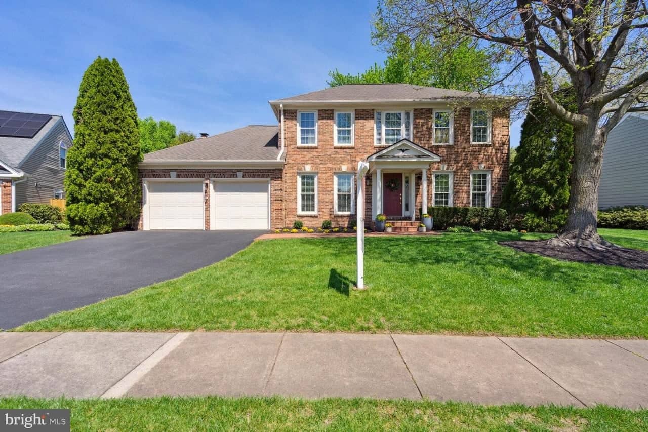 Front exterior of the brick Colonial at 13218 Topsfield Court with a two-car garage and mature front tree