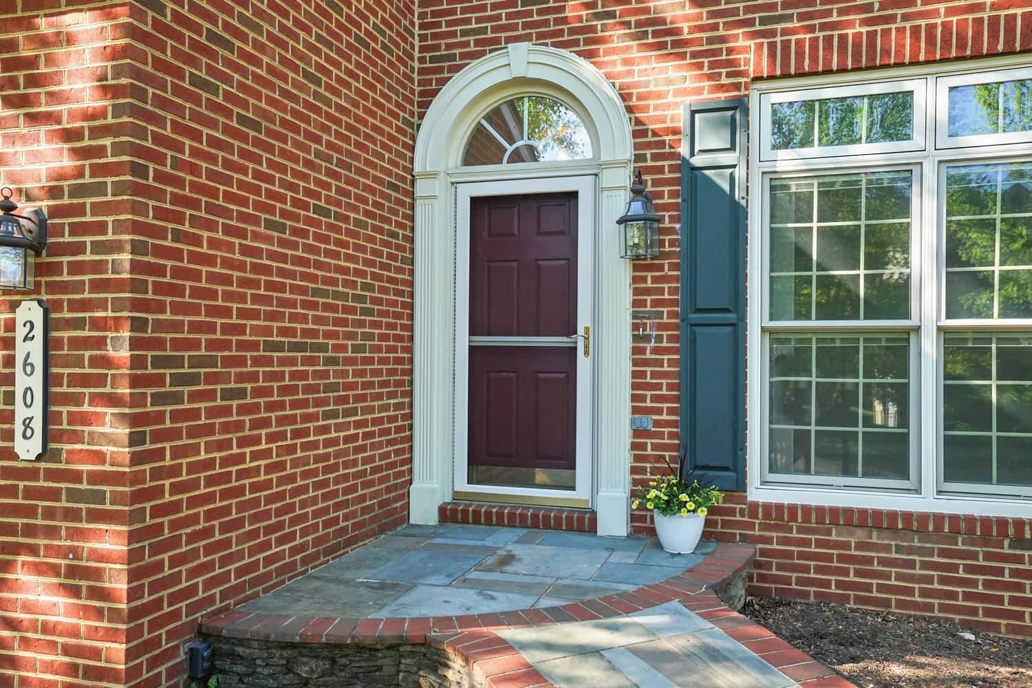 Covered brick entry at 2608 Amanda Court with arched transom, burgundy front door, and slate landing