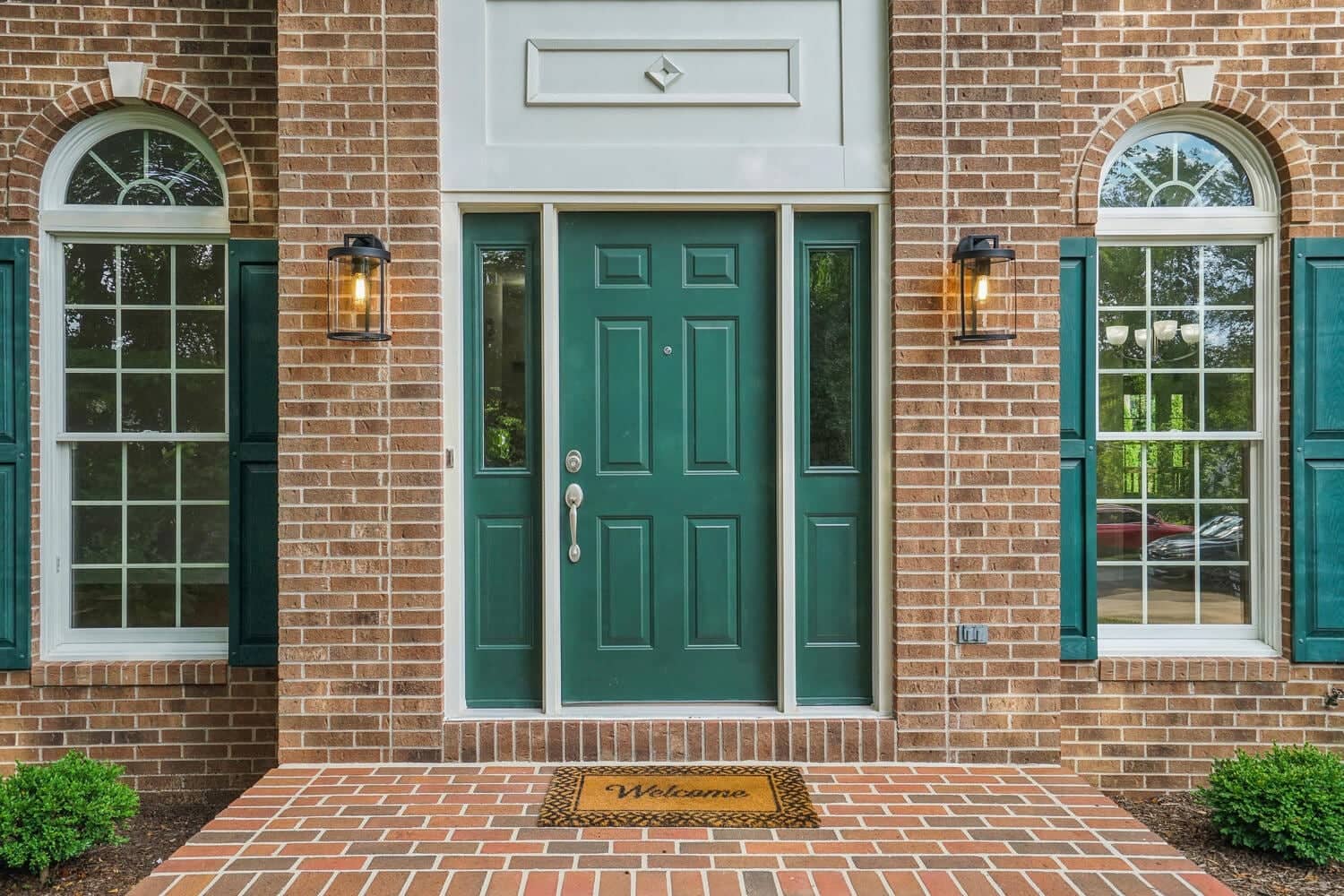 Brick entry at 4517 Forest Hill Drive with green front door, sidelights, and arched windows