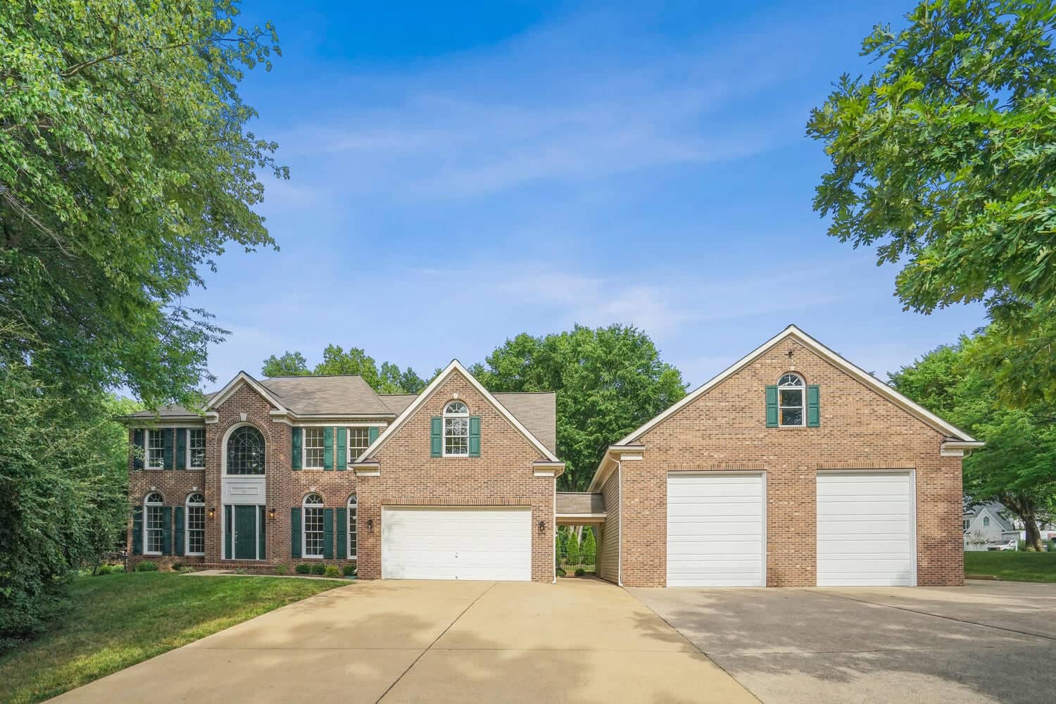 Wide front view of 4517 Forest Hill Drive with attached garage, detached garage building, and broad driveway