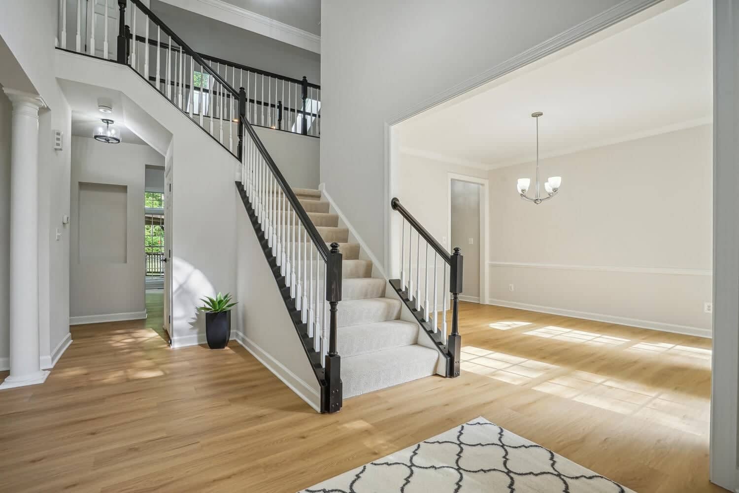 Two-story foyer at 4517 Forest Hill Drive with black-and-white staircase, wood flooring, and dining-room opening