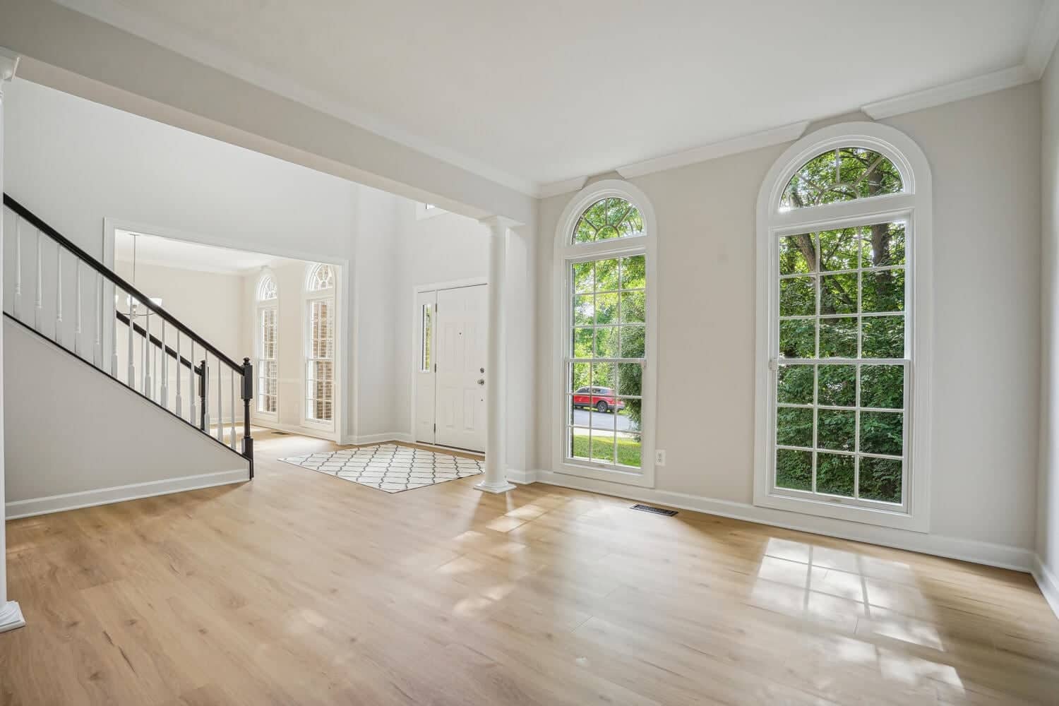 Bright formal living room at 4517 Forest Hill Drive with tall arched windows and view toward the foyer