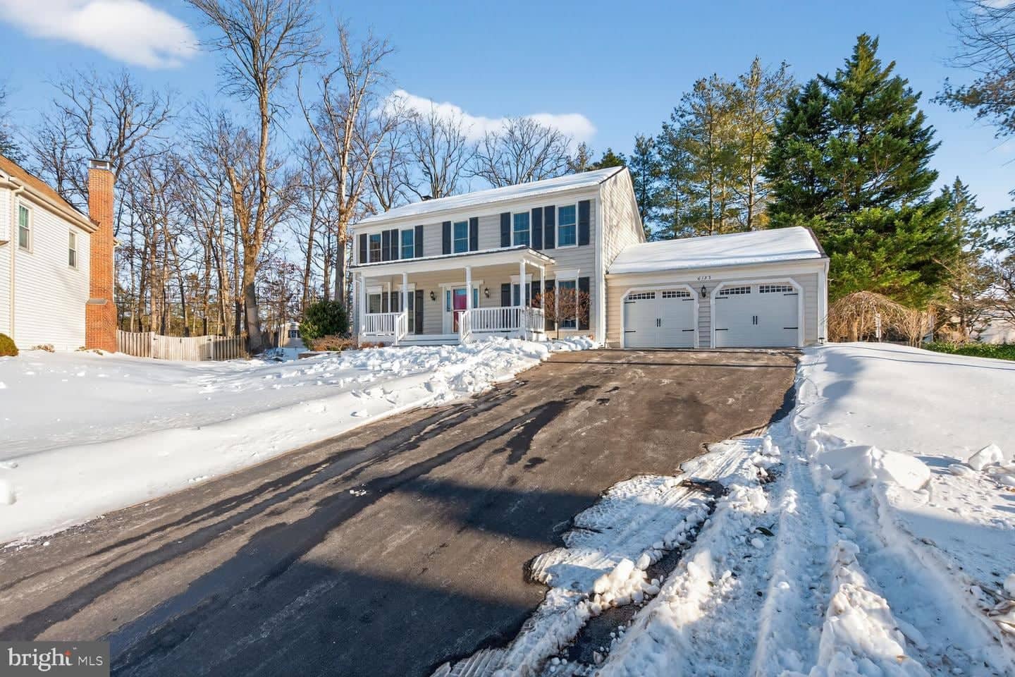 Wide streetside view of 6125 Sandstone Court, its driveway, and attached garage in winter