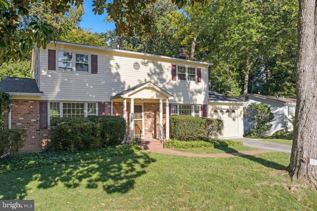 Angled front view with lawn, mature trees, and attached garage at 6814 Grey Fox Drive