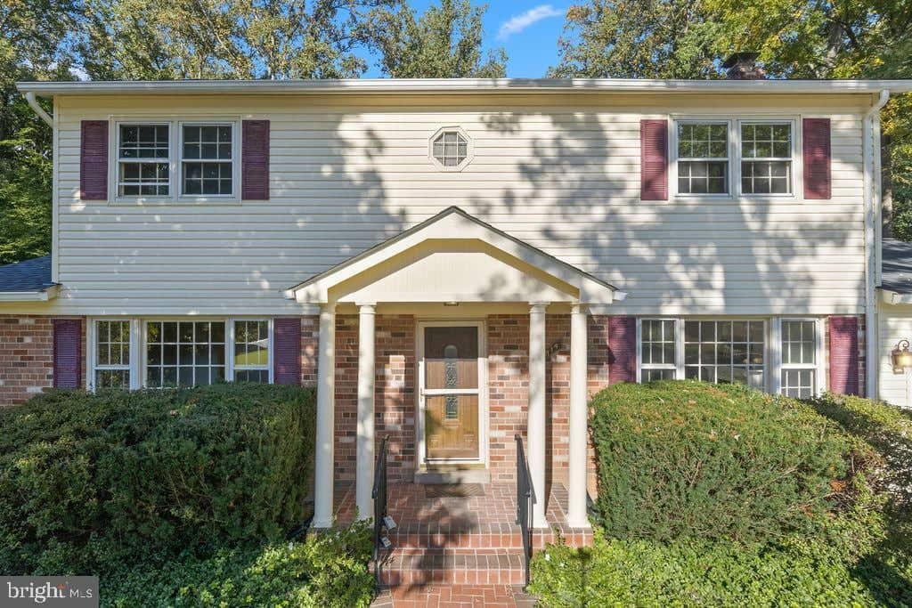 Covered front entry framed by brick columns and shrubs at 6814 Grey Fox Drive