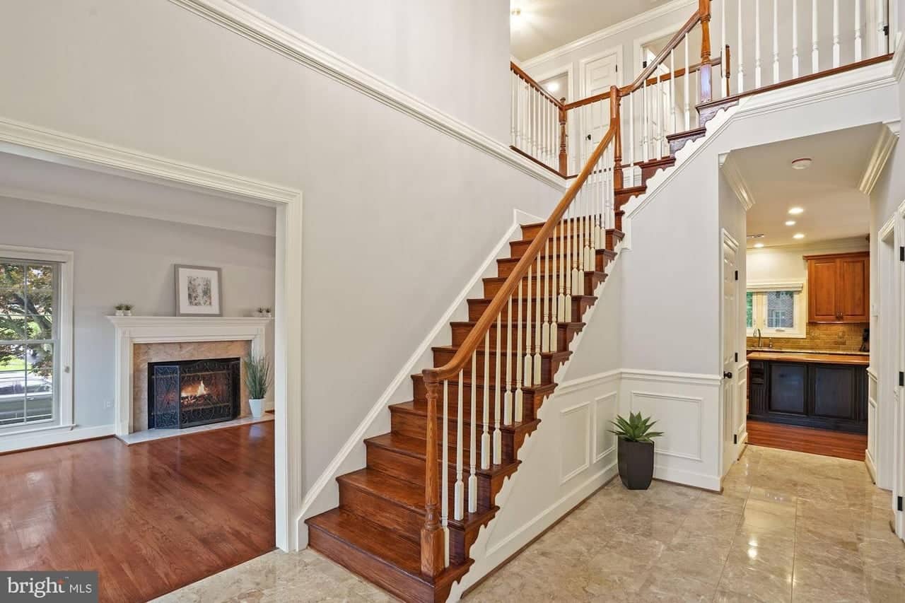 Two-story foyer with hardwood staircase, wainscoting, and views into the living room and kitchen