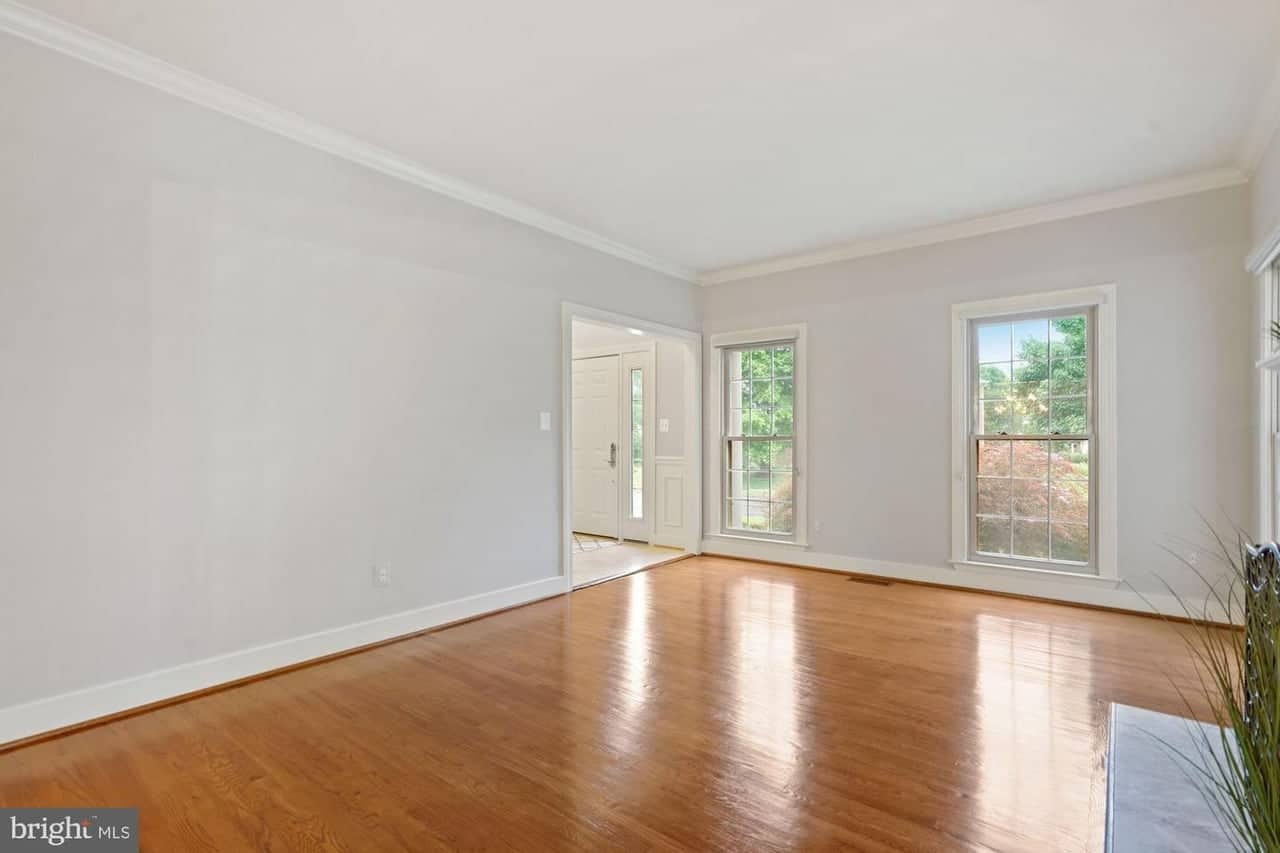 Second living-room view with hardwood floors and windows flanking the fireplace