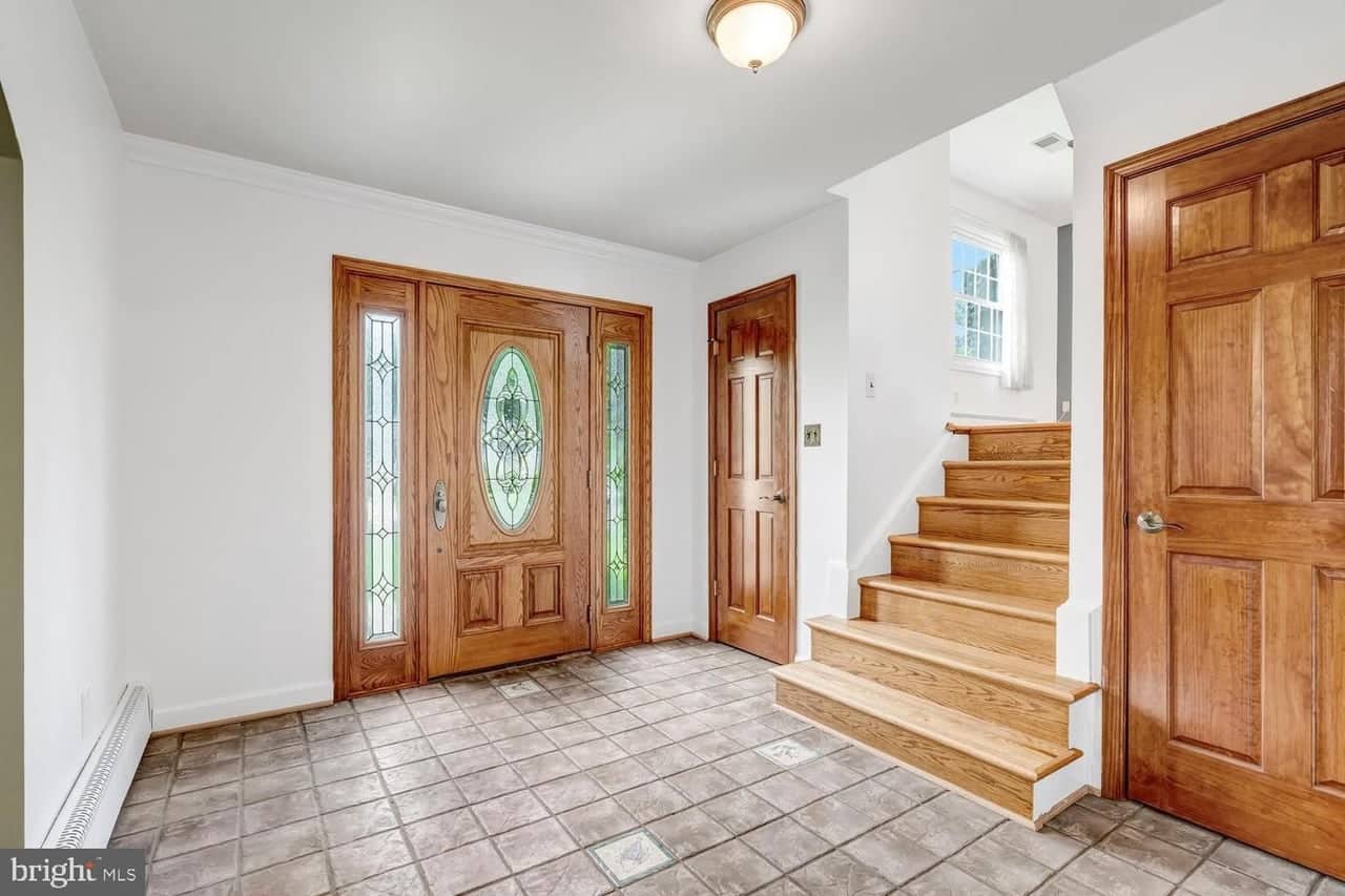 Entry foyer with decorative wood front door, tile floor, and hardwood stairs