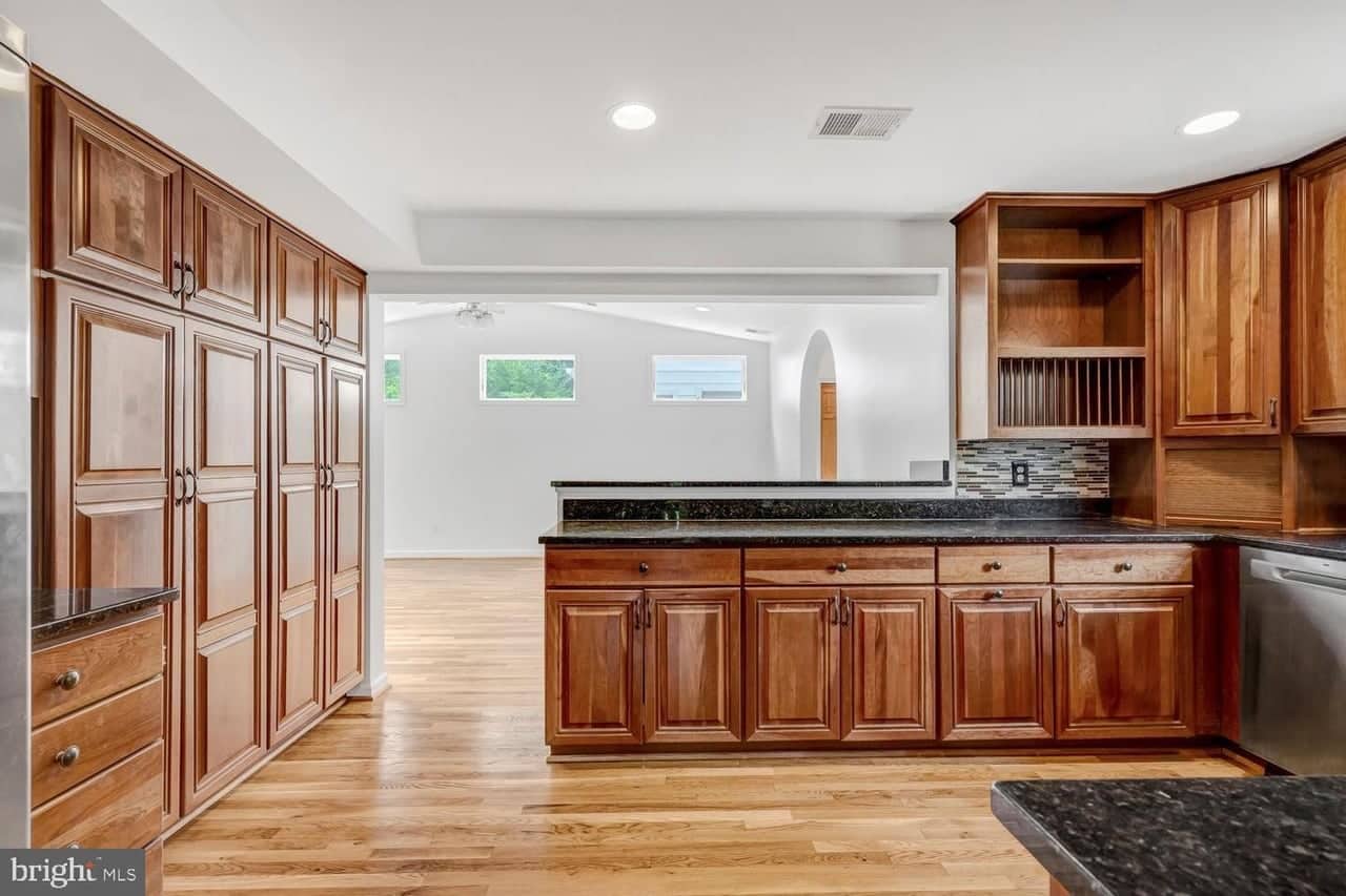 Kitchen with extensive wood cabinetry, granite counters, and a pass-through to the family-room addition