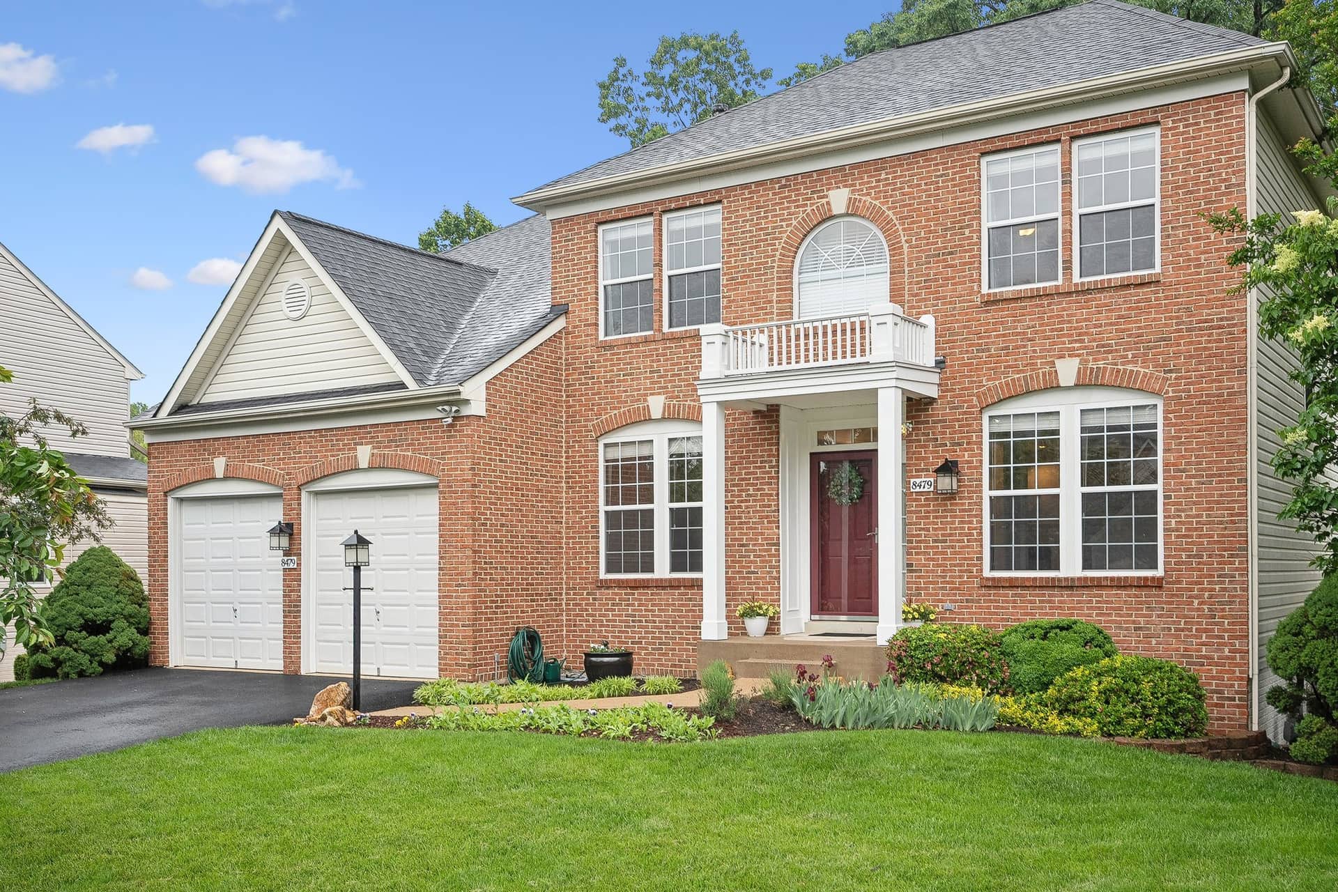 Front exterior of the brick Colonial at 8479 Catia Lane with a two-car garage and landscaped lawn
