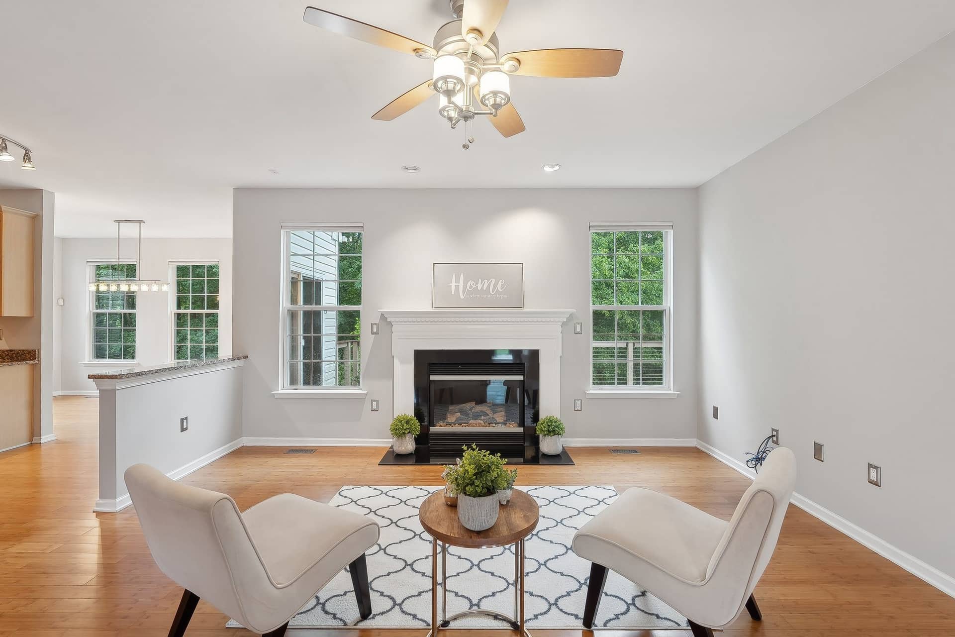 Living room at 8479 Catia Lane with a gas fireplace, hardwood floor, and three windows facing the trees