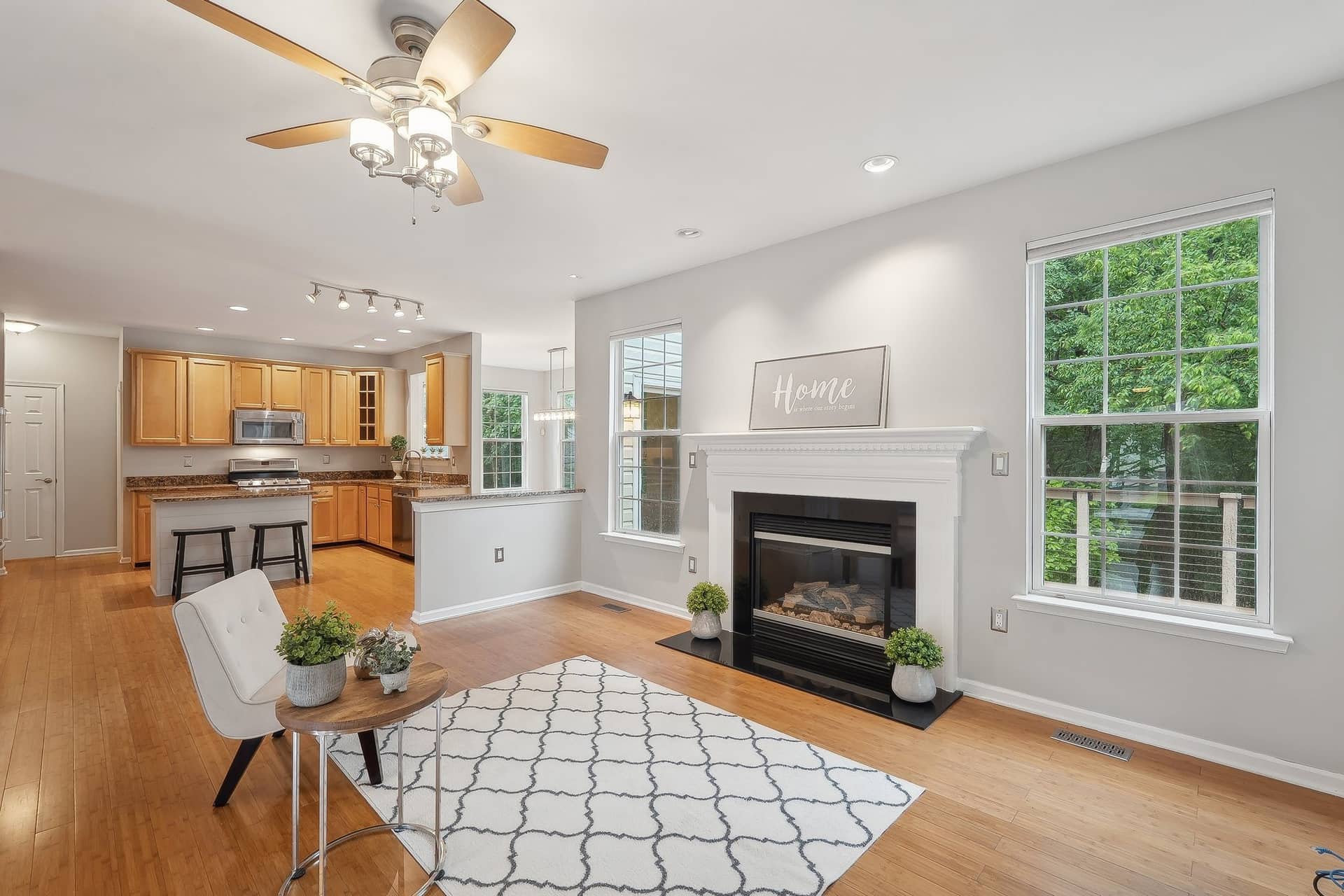 Living room viewed toward the open kitchen with a gas fireplace and hardwood flooring