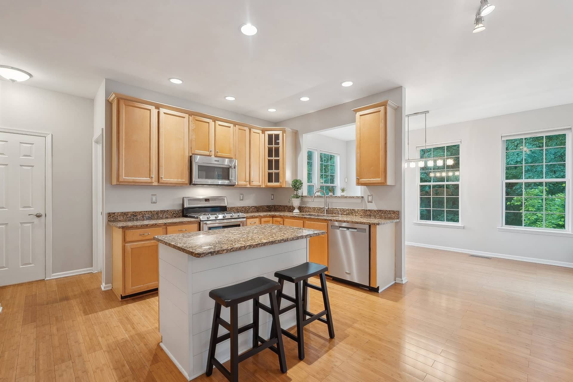 Kitchen with granite counters, wood cabinetry, stainless-steel appliances, and a center island