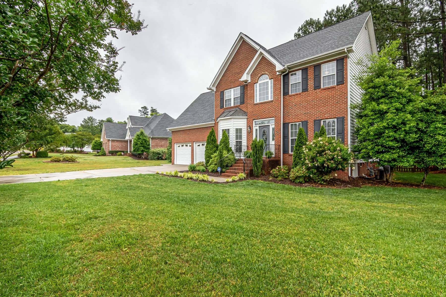 Two-story brick Colonial with black shutters and a tree-framed lawn — architectural inspiration