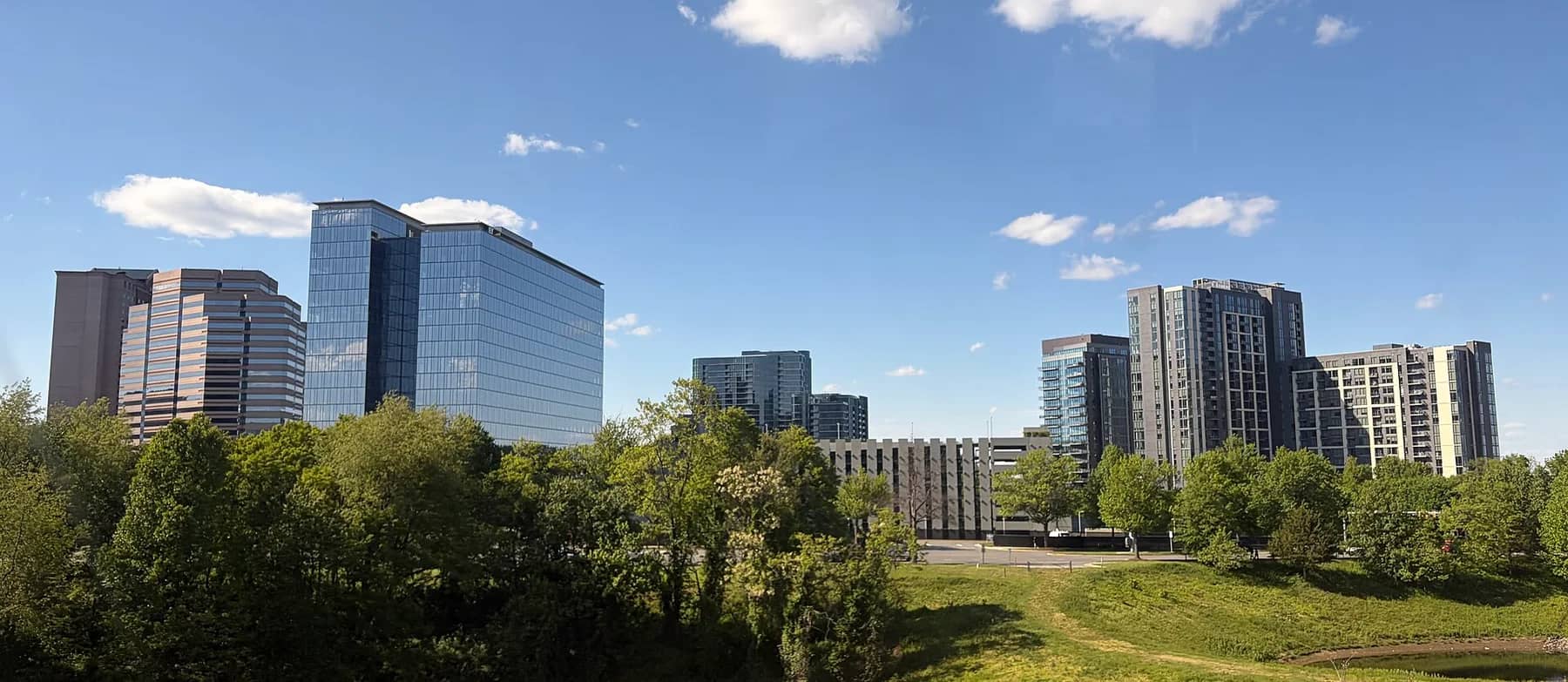 Office and residential towers above green trees and an open lawn in Tysons, Virginia