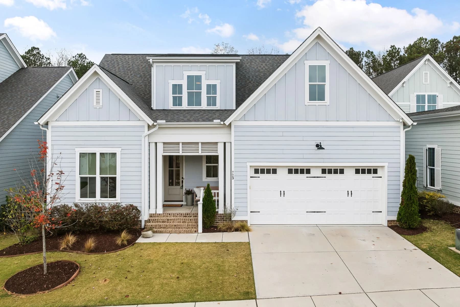 Gray and white gabled home with a covered front porch and landscaped lawn — architectural inspiration