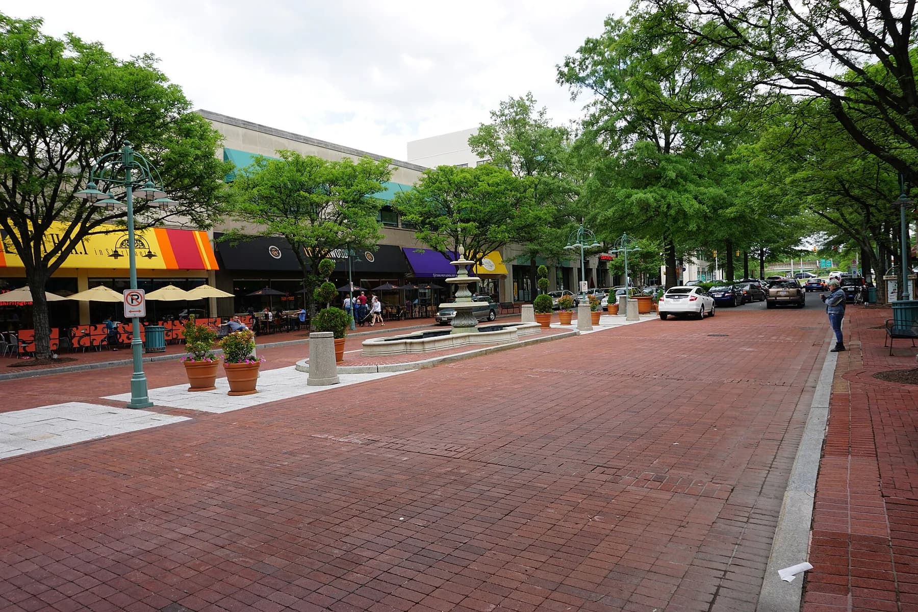 Fountain, leafy trees, and outdoor restaurant seating on Campbell Avenue in Shirlington