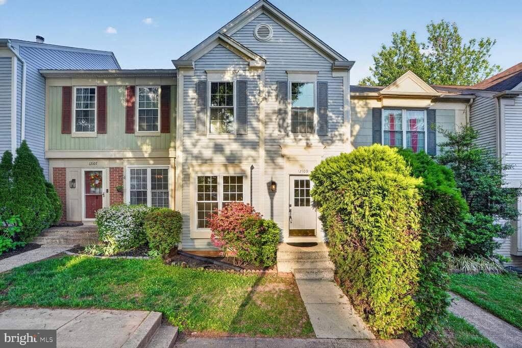 Front exterior of 12109 Wedgeway Place with gray siding, brick accents, and a landscaped entry walk