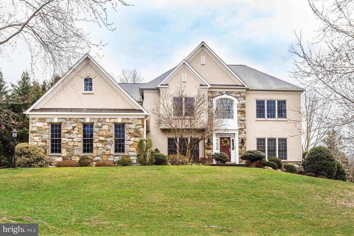 Front exterior of 12803 Holly Grove Court with stone-and-stucco facade, landscaped lawn, and mature trees