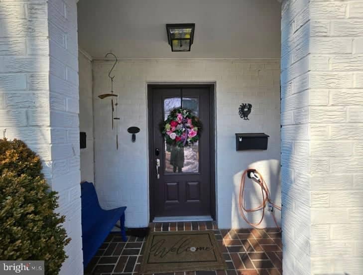 Covered brick entry at 315 N Maple Avenue with a dark front door, bench, and floral wreath