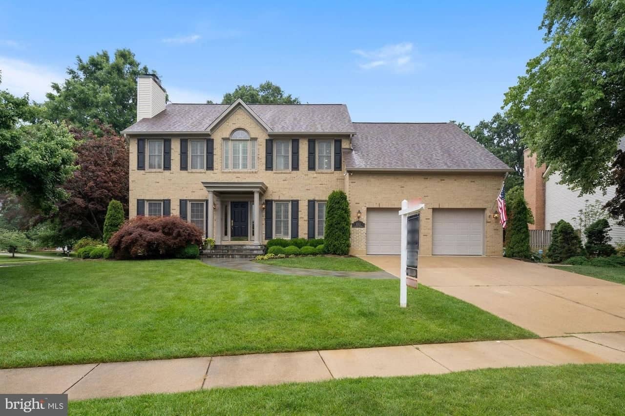 Front exterior of 8312 Rampart Court with brick facade, landscaped lawn, and two-car garage