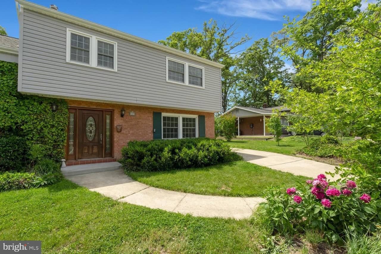 Front exterior of 8339 Wagon Wheel Road with brick lower level, siding, and landscaped walk